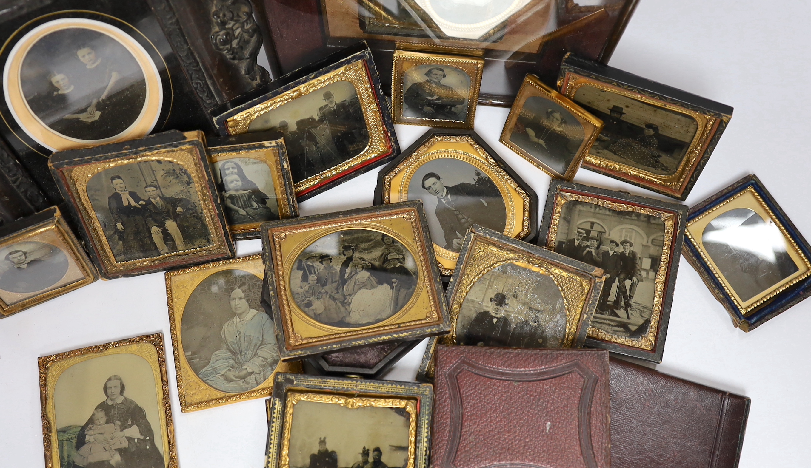 A collection of mid 19th century ambrotype portrait photographs, all mounted in brass etc frames, some in decorative cases, two examples framed (25)